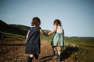2 girls holding hands walking
